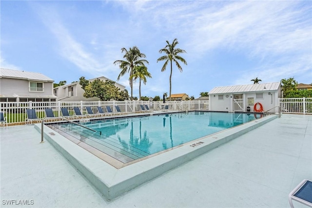 pool featuring an outbuilding, a patio area, and fence