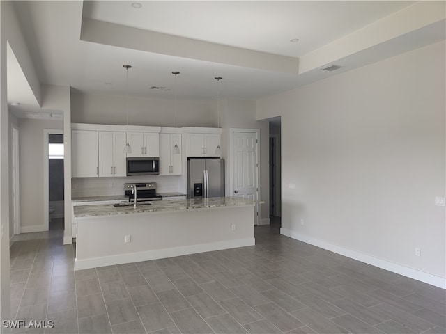 kitchen featuring pendant lighting, stainless steel appliances, white cabinets, and a center island with sink