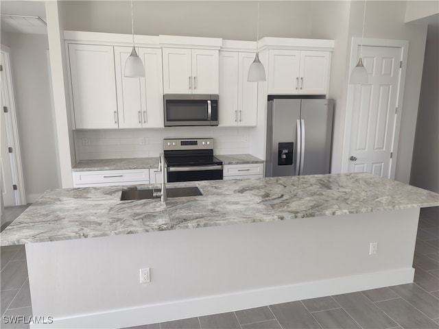 kitchen featuring decorative backsplash, stainless steel appliances, white cabinetry, and a kitchen island with sink