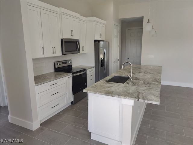 kitchen with white cabinetry, an island with sink, light stone counters, stainless steel appliances, and sink