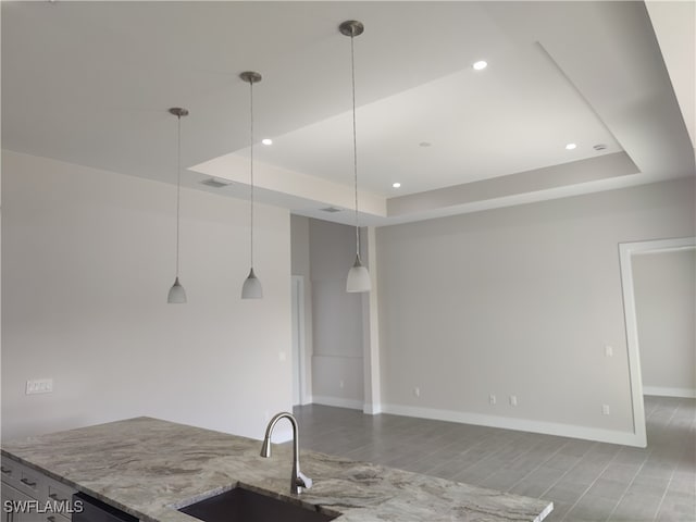 kitchen with a raised ceiling, hanging light fixtures, hardwood / wood-style floors, and sink