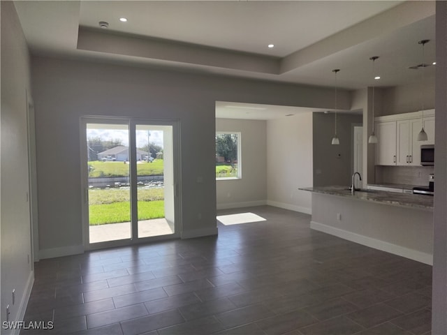 unfurnished living room featuring a raised ceiling and sink