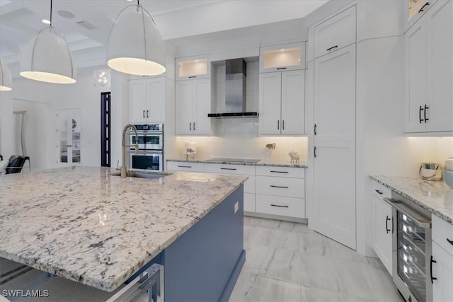 kitchen featuring black electric stovetop, stainless steel double oven, beverage cooler, marble finish floor, and wall chimney range hood