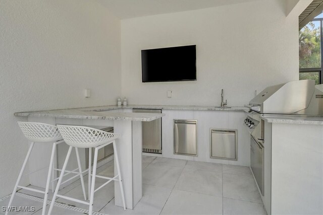 interior space with exterior kitchen, outdoor wet bar, a sink, and grilling area