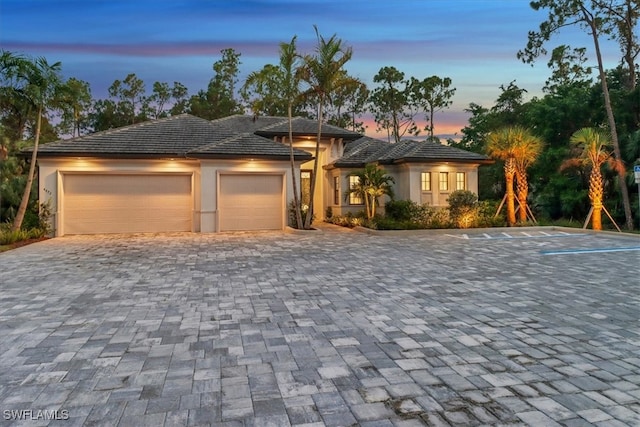 view of front of home with a garage, decorative driveway, and stucco siding