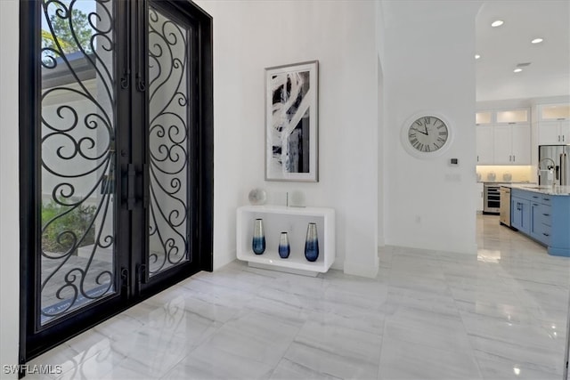 entryway with marble finish floor, wine cooler, and recessed lighting