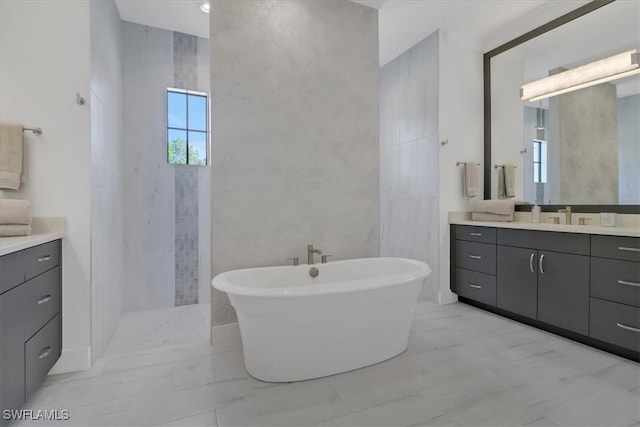 full bathroom featuring a freestanding bath, marble finish floor, walk in shower, and vanity