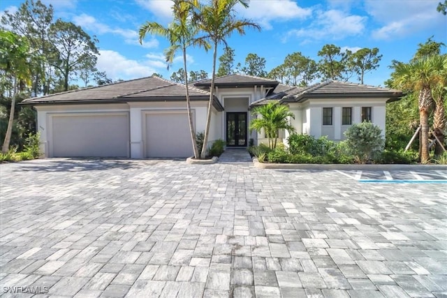 prairie-style home with decorative driveway, an attached garage, and stucco siding