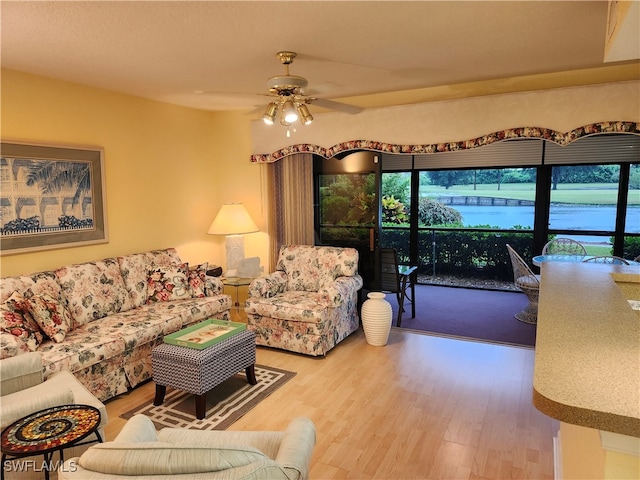 living room with ceiling fan, wood-type flooring, a healthy amount of sunlight, and a water view