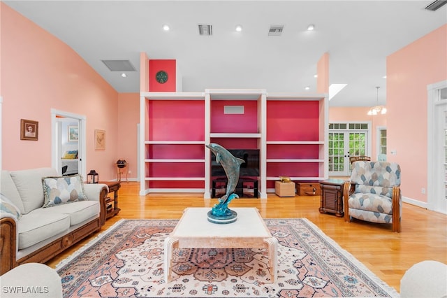 living room with a chandelier, wood-type flooring, and vaulted ceiling