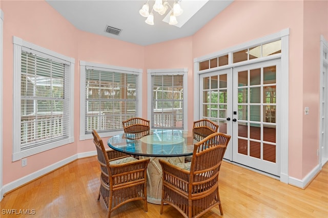 dining space with hardwood / wood-style flooring, french doors, and a notable chandelier