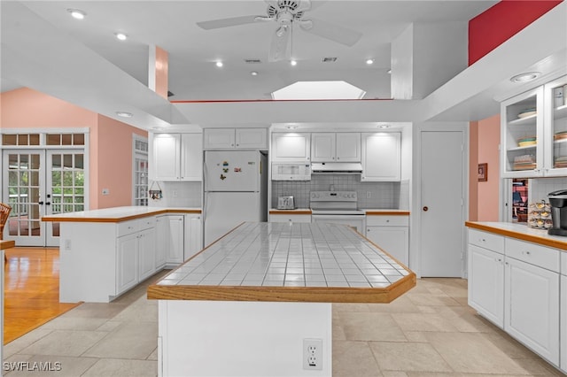 kitchen with french doors, tile counters, a center island, white appliances, and white cabinets