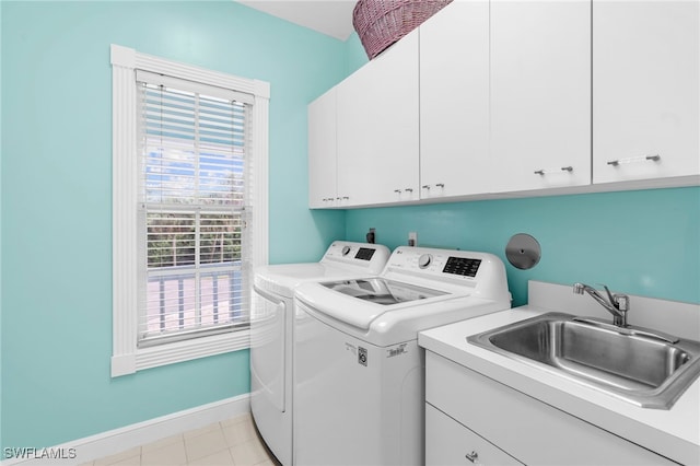 clothes washing area featuring washing machine and dryer, sink, and cabinets