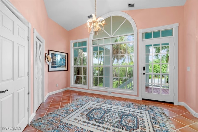 entryway featuring tile patterned flooring, plenty of natural light, lofted ceiling, and an inviting chandelier