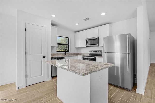 826 Yellowbird Dr, Fort Myers, FL 33913 - kitchen featuring stainless steel appliances, light stone countertops, a center island, and wood finish floors