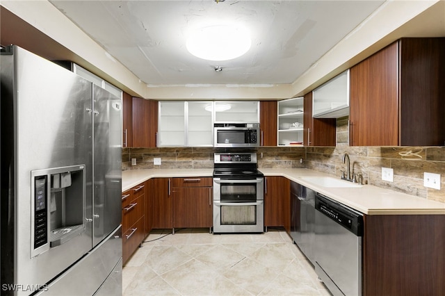 kitchen featuring appliances with stainless steel finishes, backsplash, light tile patterned floors, and sink