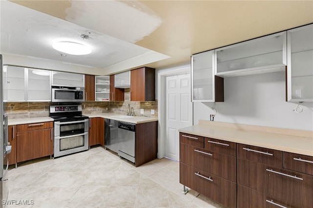 kitchen featuring sink, light tile patterned flooring, stainless steel appliances, and decorative backsplash