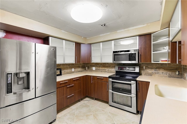 kitchen with light tile patterned flooring, stainless steel appliances, and decorative backsplash