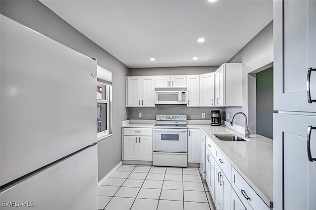 kitchen with sink, white cabinets, white appliances, and light tile patterned floors