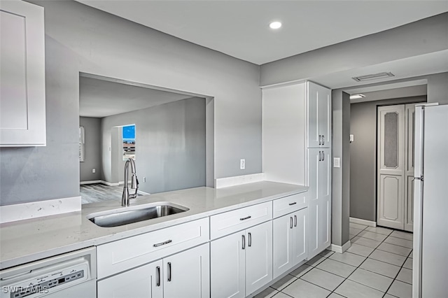 kitchen with white cabinets, sink, light tile patterned floors, dishwashing machine, and white fridge