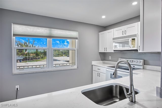 kitchen with white cabinetry, stainless steel electric range oven, sink, and light stone counters