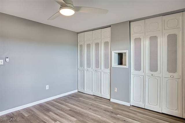 unfurnished bedroom featuring ceiling fan, light wood-type flooring, and two closets