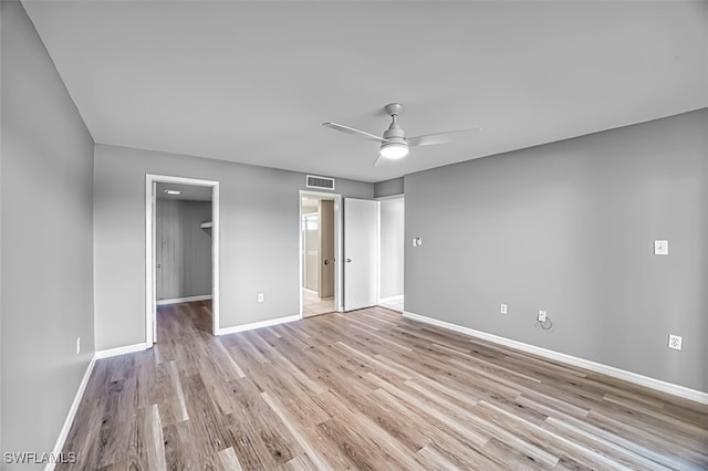 unfurnished bedroom featuring light wood-type flooring, a spacious closet, a closet, and ceiling fan