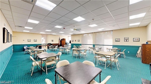 dining space with a paneled ceiling, ceiling fan, and carpet