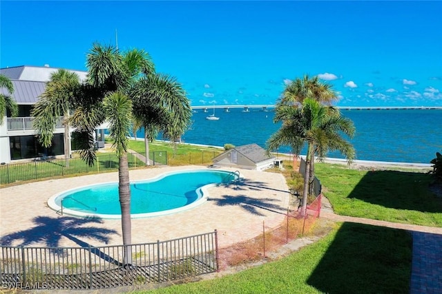 view of pool featuring a patio, a water view, and a lawn