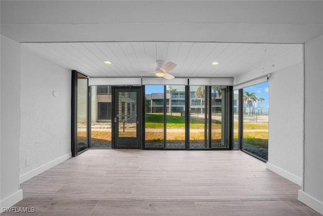 unfurnished sunroom with ceiling fan