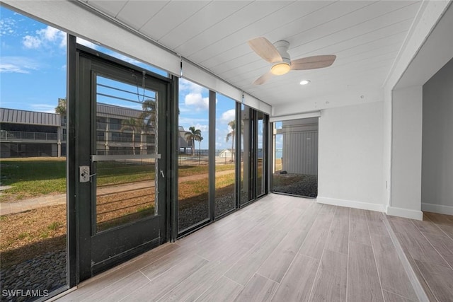 unfurnished sunroom featuring ceiling fan and a wealth of natural light