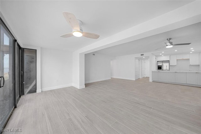 unfurnished living room featuring ceiling fan and light hardwood / wood-style flooring