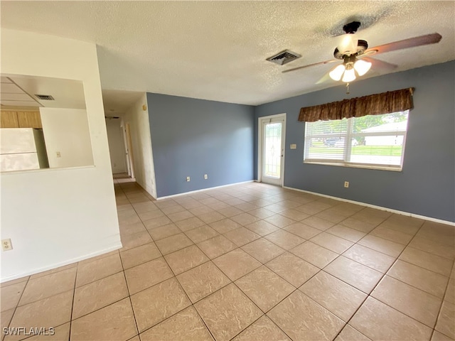 empty room with ceiling fan, light tile patterned floors, and a textured ceiling