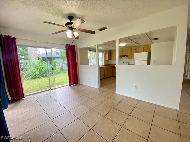 tiled empty room featuring ceiling fan and a textured ceiling