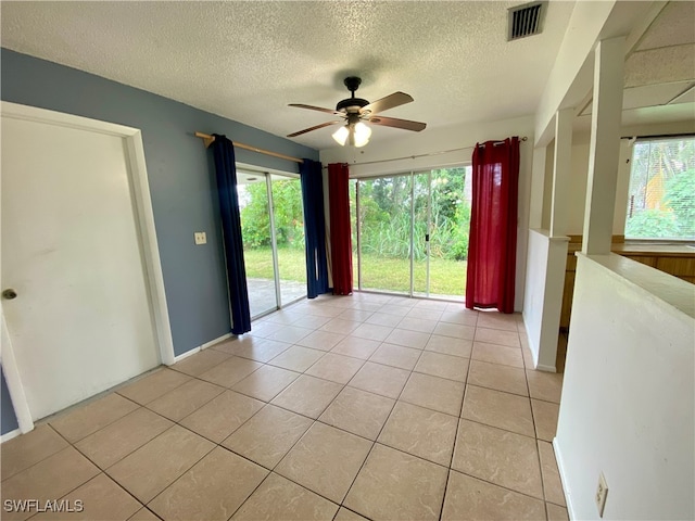 tiled empty room featuring ceiling fan and a textured ceiling