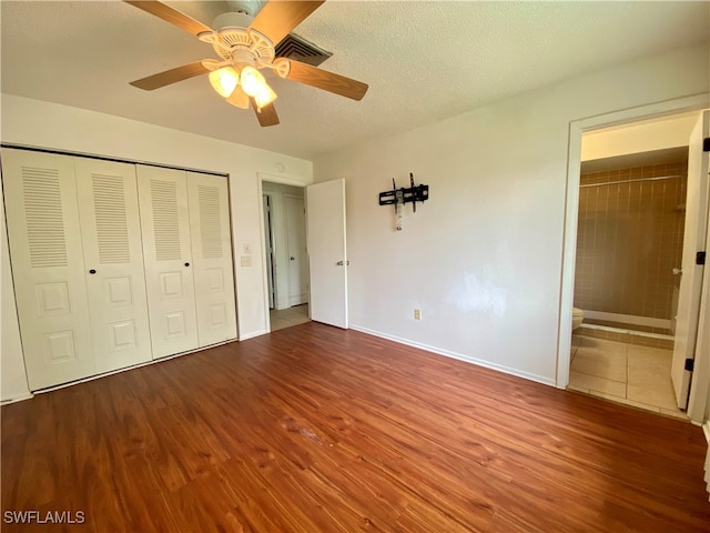 unfurnished bedroom with hardwood / wood-style floors, a textured ceiling, a closet, ceiling fan, and ensuite bathroom