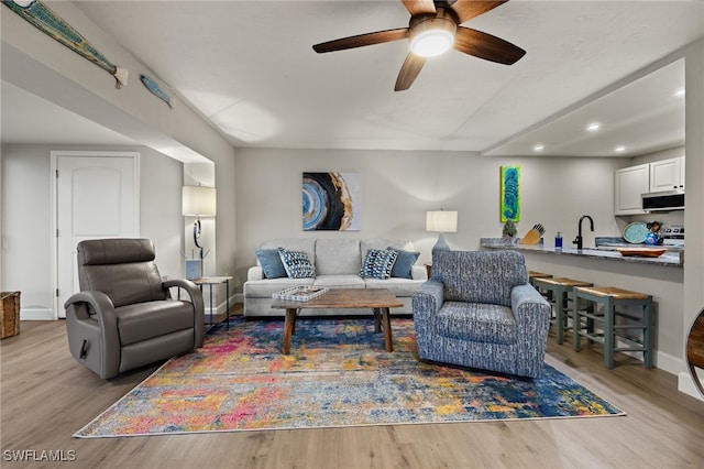 living room featuring light hardwood / wood-style floors, ceiling fan, and sink