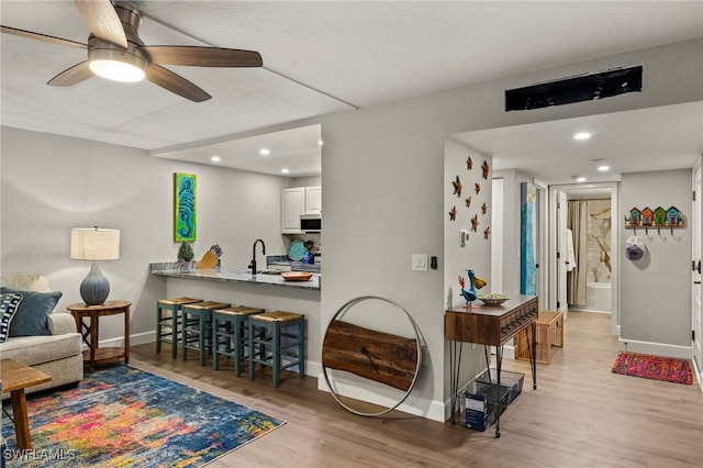 living room with sink, ceiling fan, and light hardwood / wood-style floors