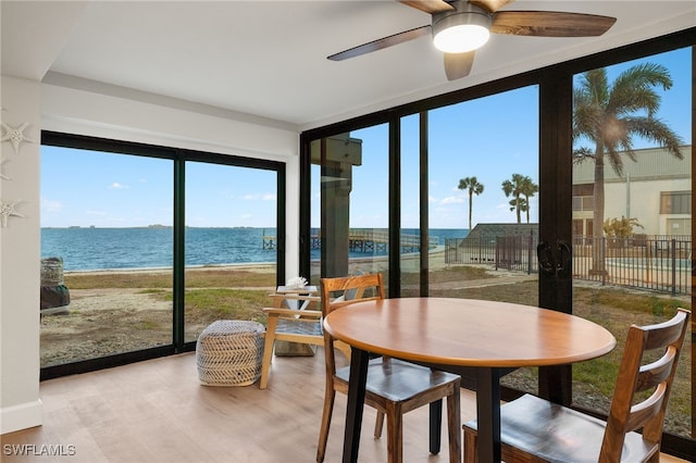 sunroom / solarium featuring ceiling fan and a water view