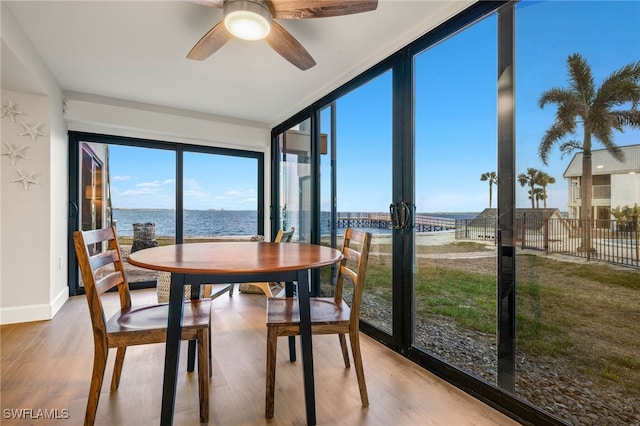 sunroom featuring ceiling fan and a water view