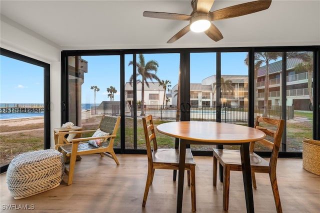 sunroom featuring ceiling fan, plenty of natural light, and a water view