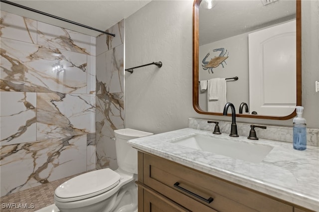 bathroom featuring toilet, tiled shower, and vanity