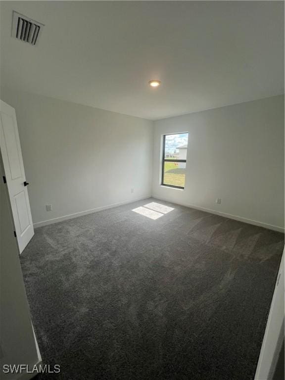 spare room with dark carpet