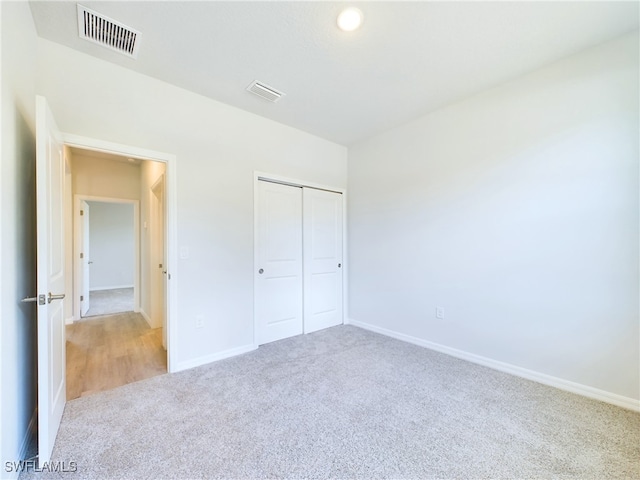 unfurnished bedroom with a closet and light colored carpet