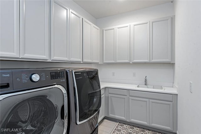 laundry area featuring cabinet space, washing machine and dryer, and a sink