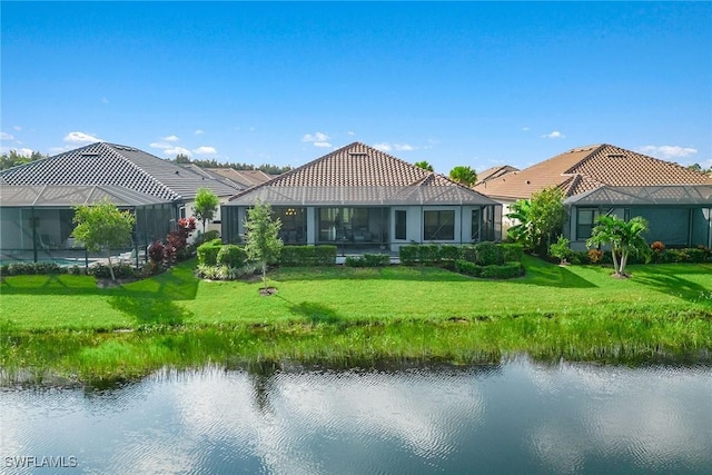 back of house featuring a yard, a water view, and a tile roof