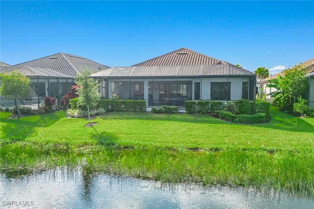 rear view of property with a tile roof, stucco siding, a water view, a lawn, and a lanai