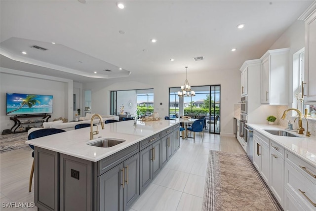 kitchen featuring a raised ceiling, a sink, visible vents, and white cabinets