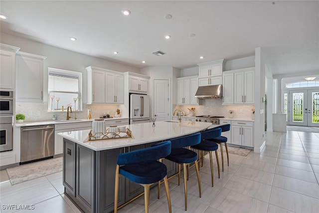 kitchen featuring a sink, under cabinet range hood, stainless steel dishwasher, and high end white fridge