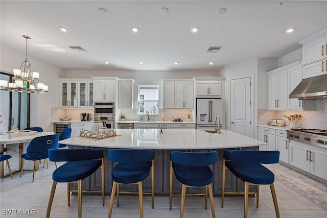 kitchen with a spacious island, visible vents, appliances with stainless steel finishes, white cabinets, and a sink